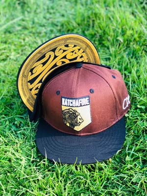The Katchafire X Calibis Snapback Cap is a custom designed cap, with a gold maori designed print on the underside of peak.  Shield emblem embroidered.